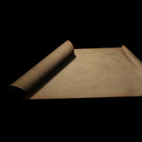 halb aufgerollte, gut erhaltene antike Schriftrolle aus Pergament vor schwarzem Hintergrund